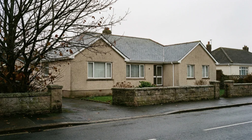 A quiet residential street in Jersey, Channel Islands, showing the exterior of a mid-century apartment block on a grey overca