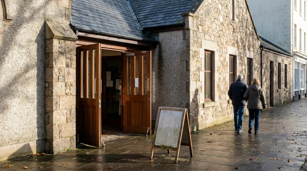 The entrance to Jersey Library in St Helier on a bright autumn morning, with the doors open and a small A-frame sign on the p