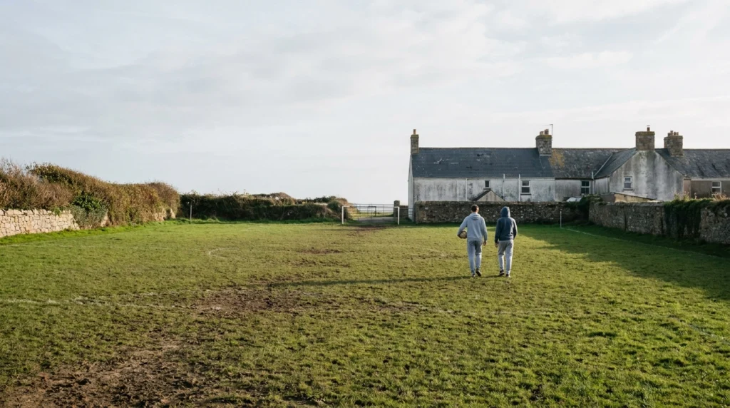 A worn but well-kept grass football pitch in Jersey, Channel Islands, photographed on a bright autumn afternoon.